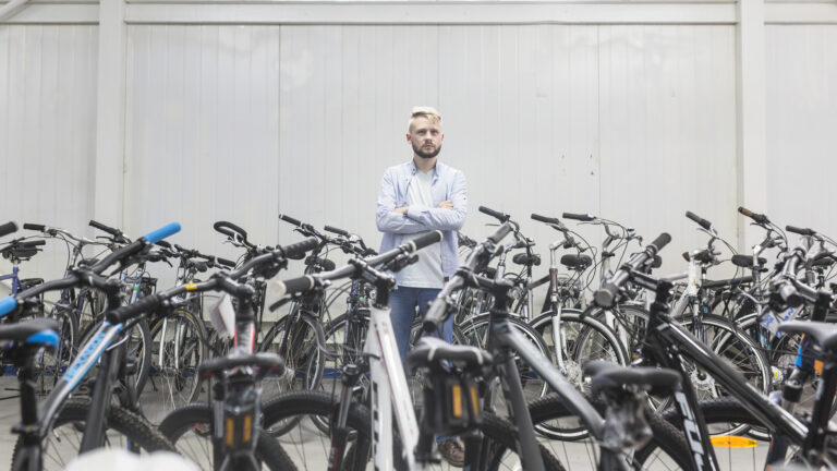 various-bicycles-surrounding-male-mechanic-standing-workshop